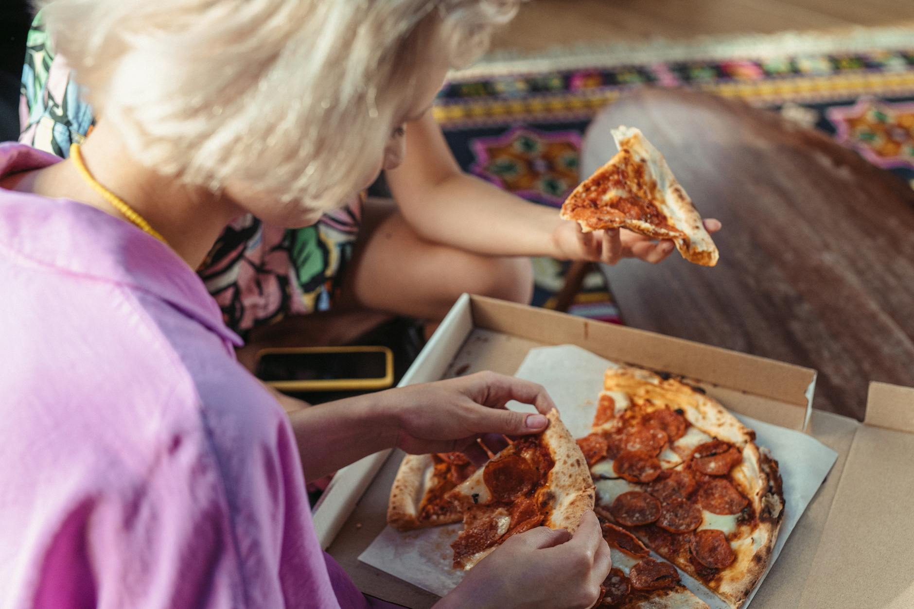 Dlaczego pizza al metro z Kampanii to idealny kompromis między street foodem a ucztą dla ekipy Dwóch przyjaciół je pizzę pepperoni przy stole w swobodnej atmosferze
