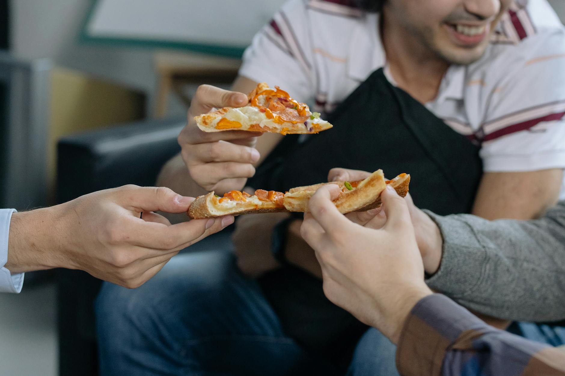 Grupa przyjaciół dzieląca się kawałkami pizzy al metro przy stole