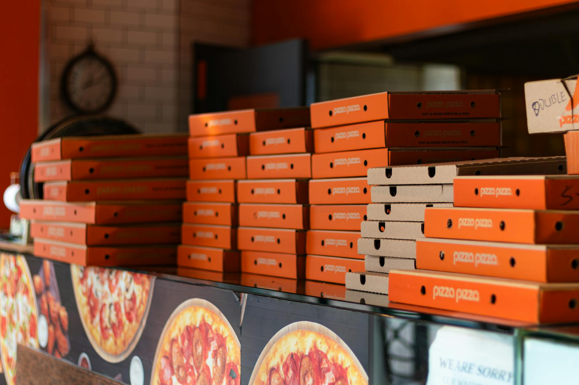 Stos pudełek na pizzę w pomarańczowych kolorach w miejskiej pizzerii