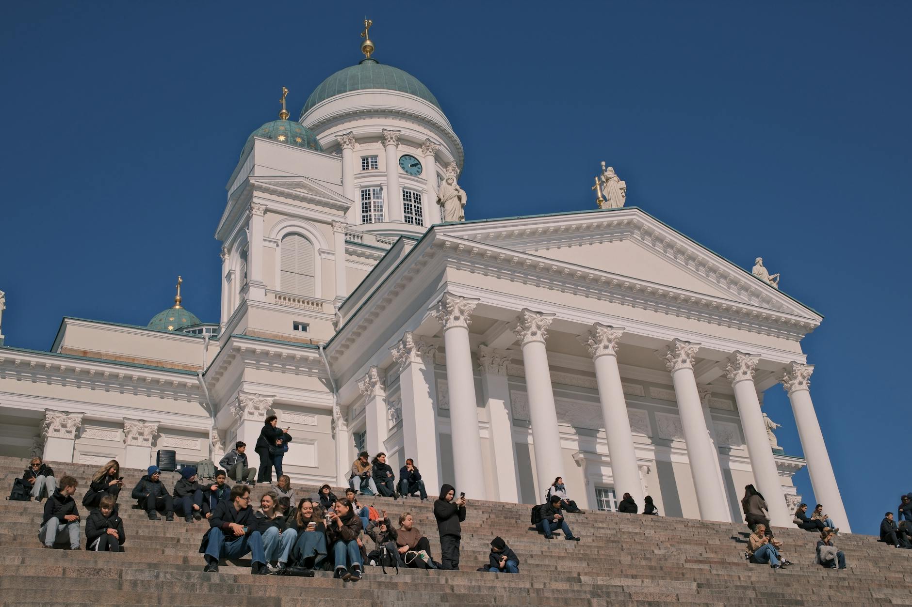 Weekend w Helsinkach z dzieckiem – praktyczny przewodnik dla rodzin podróżujących po Finlandii Ludzie odpoczywający na schodach katedry w Helsinkach w słoneczny dzień