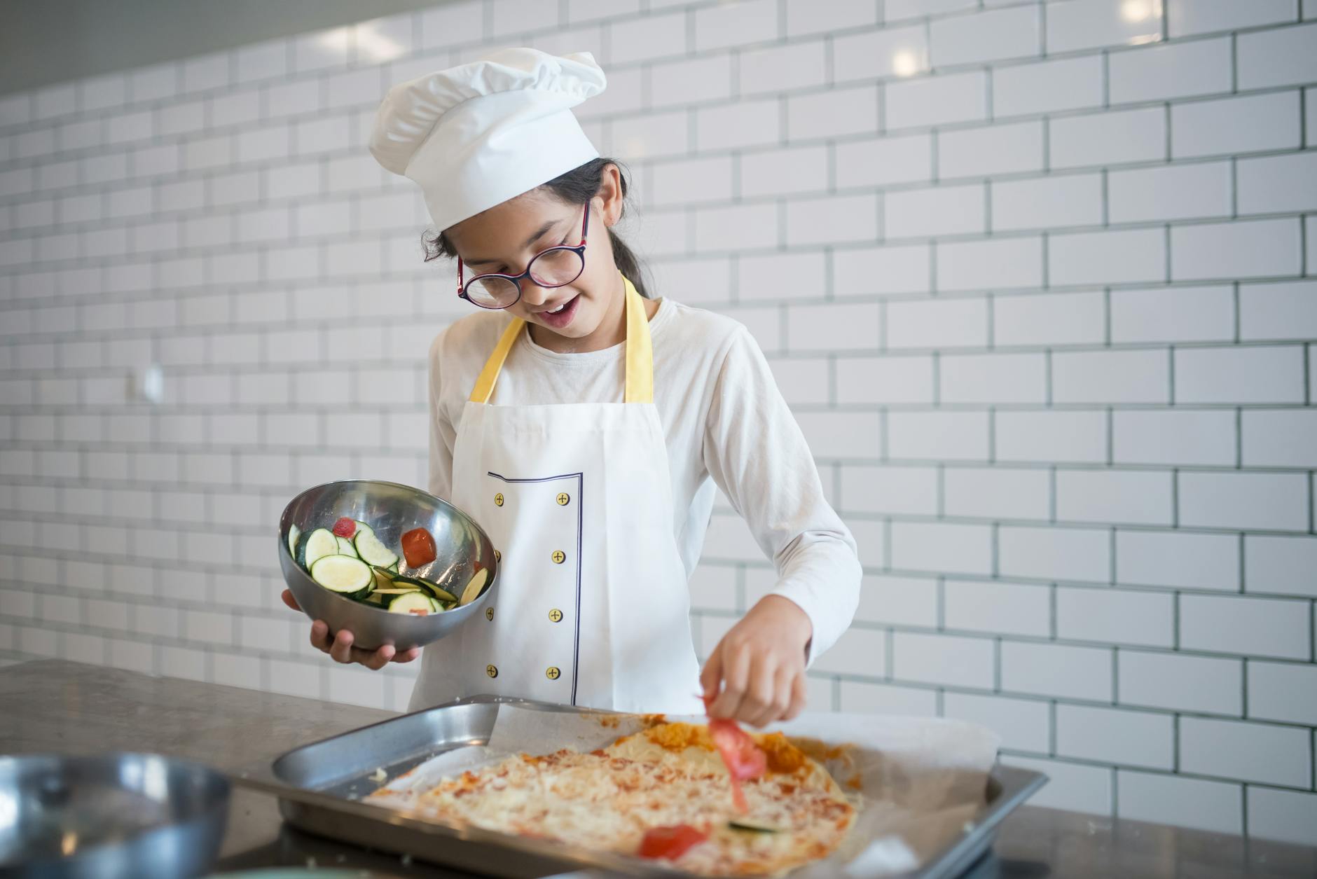 Młody kucharz układa świeże składniki na domowej pizzy w nowoczesnej kuchni