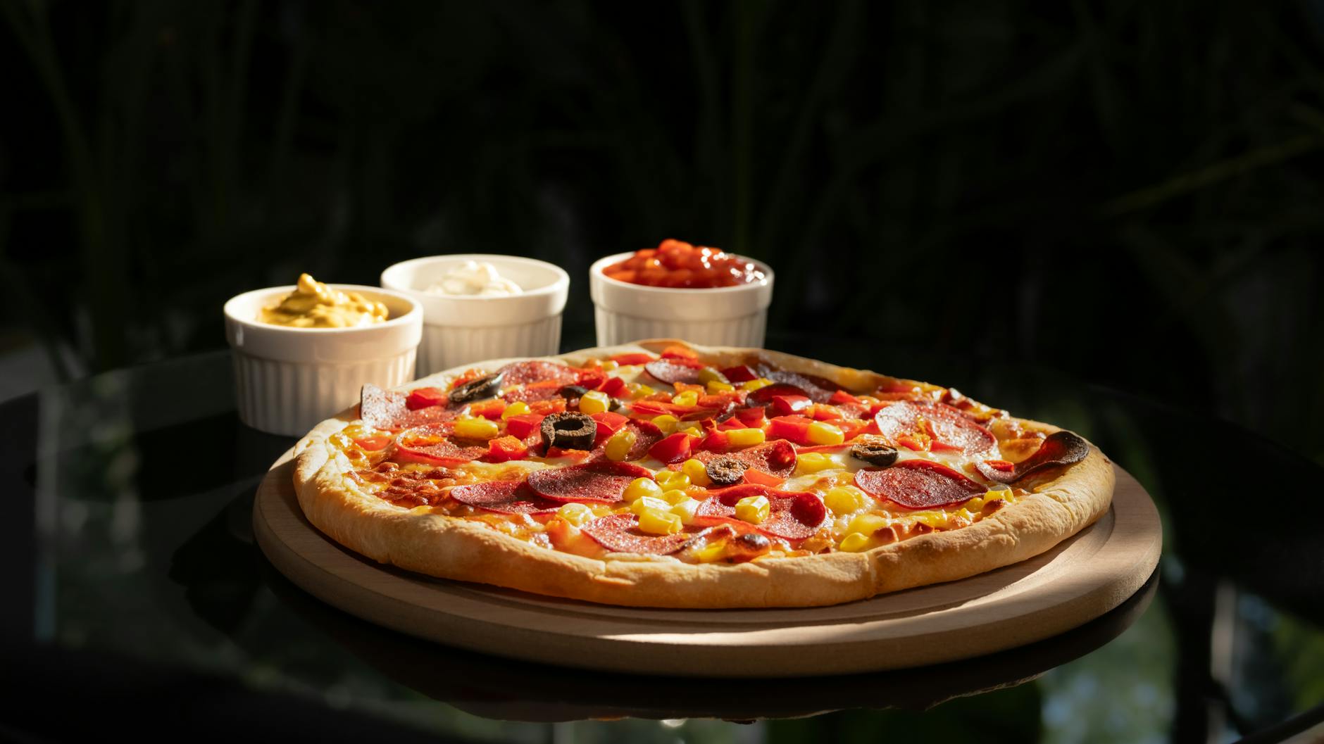 Pizza pepperoni na talerzu z miseczkami sosów i dodatków