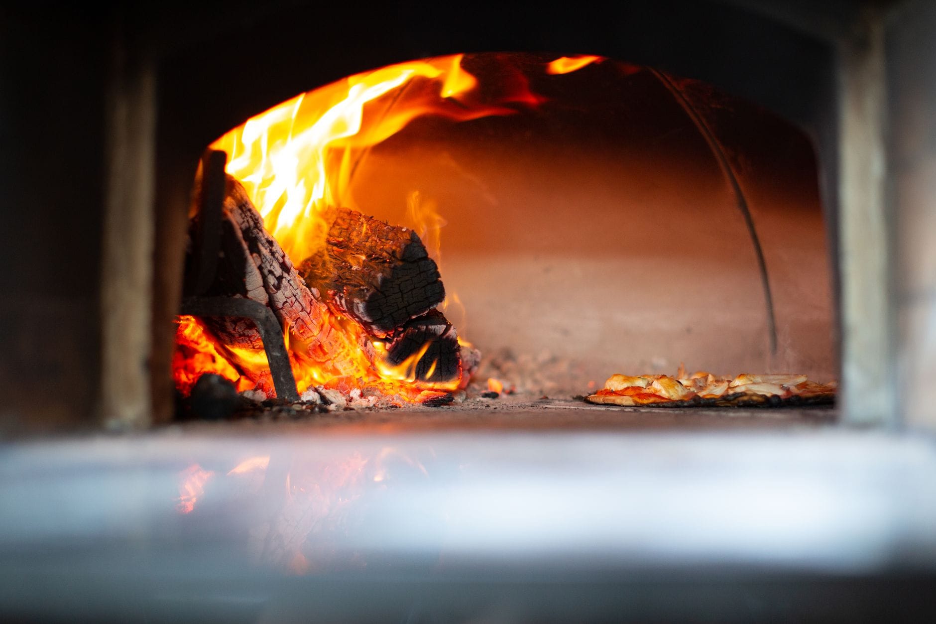 Pizza pieczona w tradycyjnym piecu opalanym drewnem z widocznym ogniem