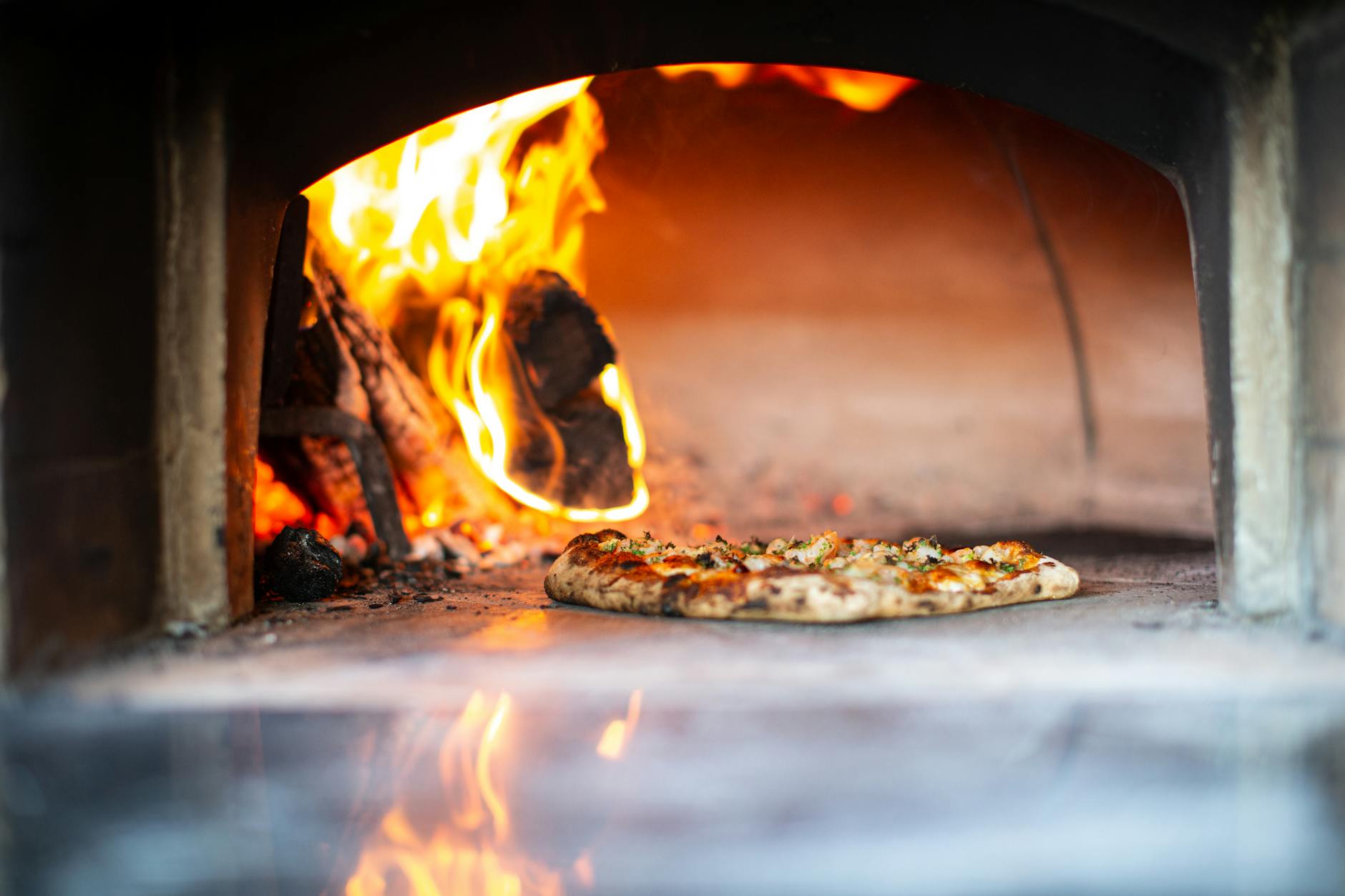 Pizza w tradycyjnym piecu opalanym drewnem z widocznym płomieniem