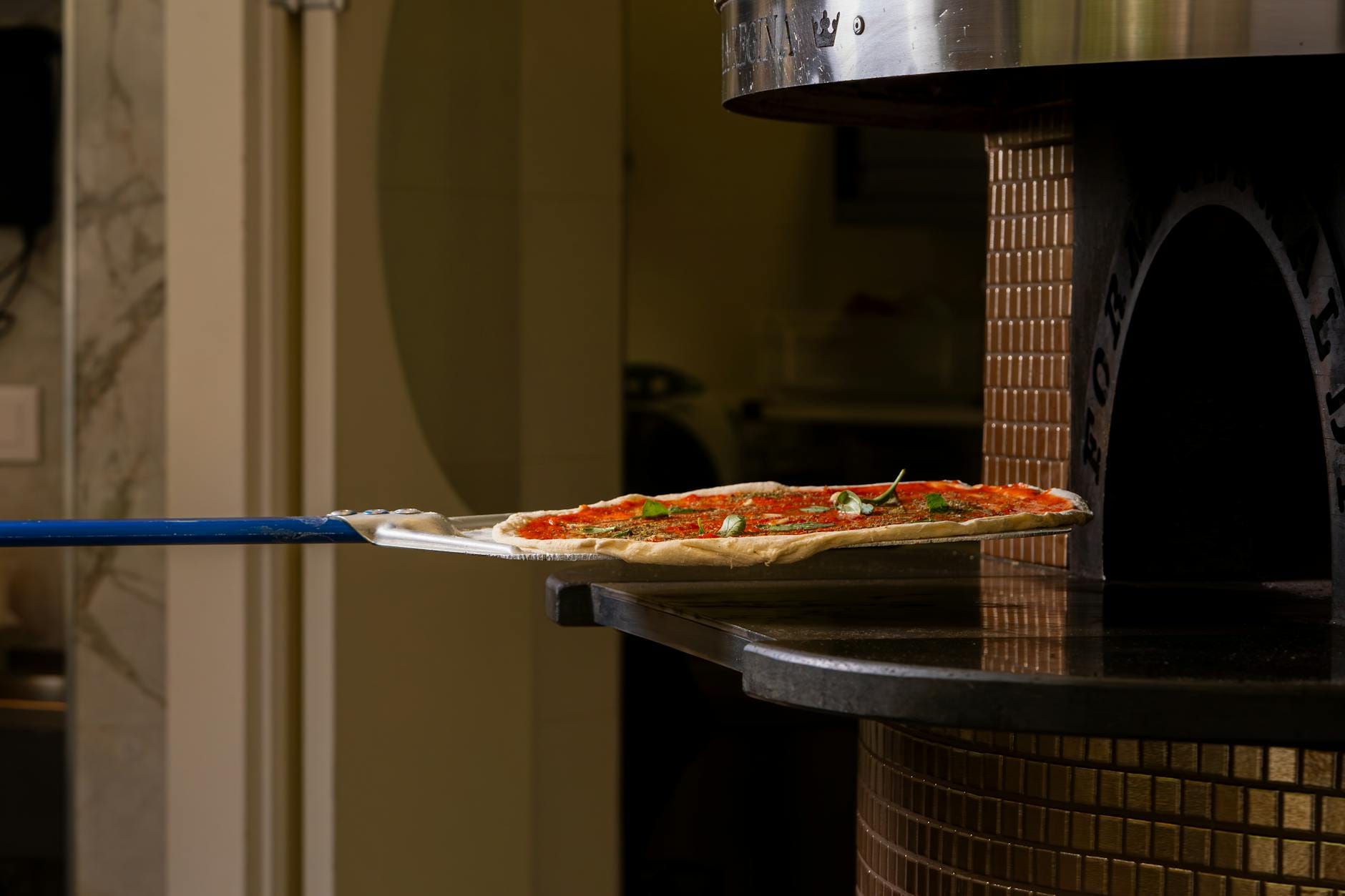 Pizza wsuwana do pieca opalanego drewnem przed domowym wypiekiem