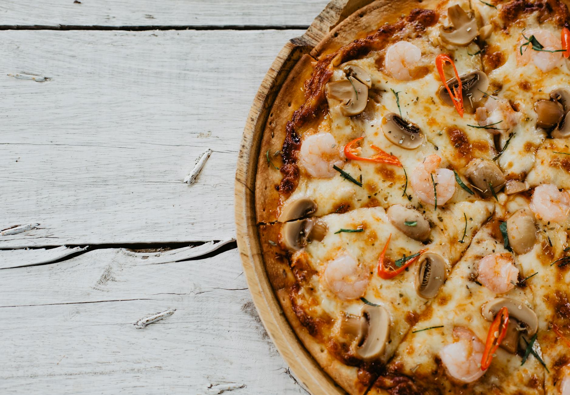 Pizza z krewetkami, pieczarkami i chili na drewnianej desce
