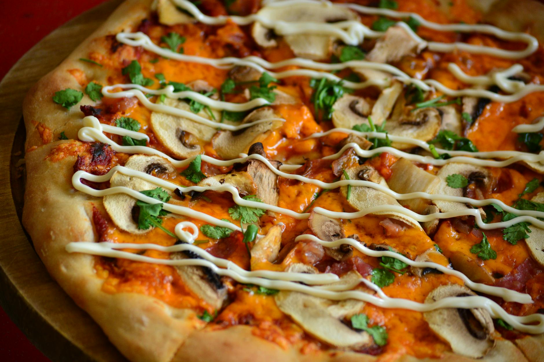 Zbliżenie na pizzę z pieczarkami, kremowym sosem i świeżymi ziołami