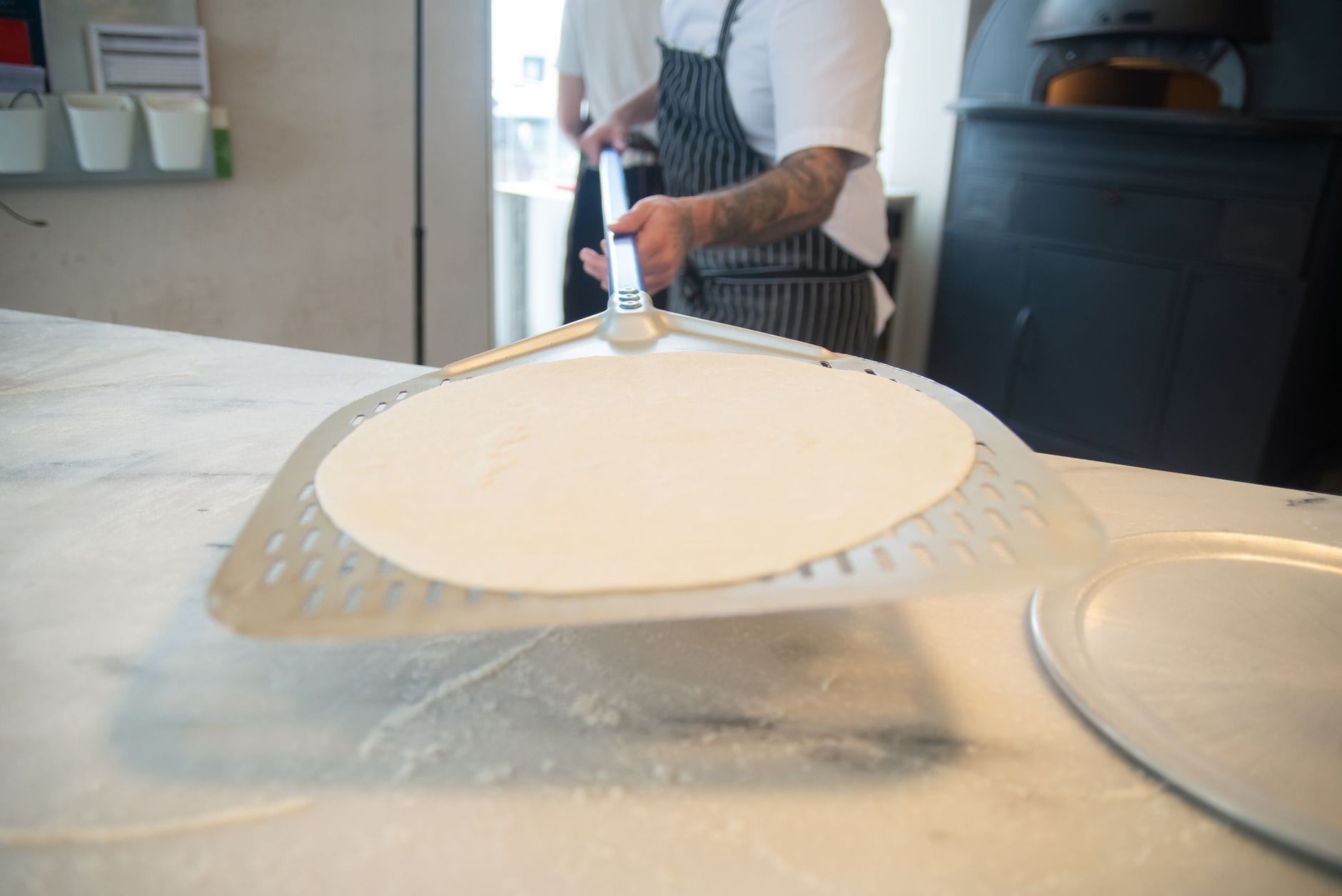 Kucharz formuje ciasto na pizzę w profesjonalnej kuchni