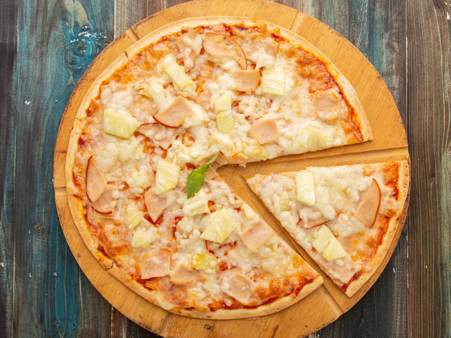 Pizza hawajska z ananasem i szynką na drewnianej desce z góry