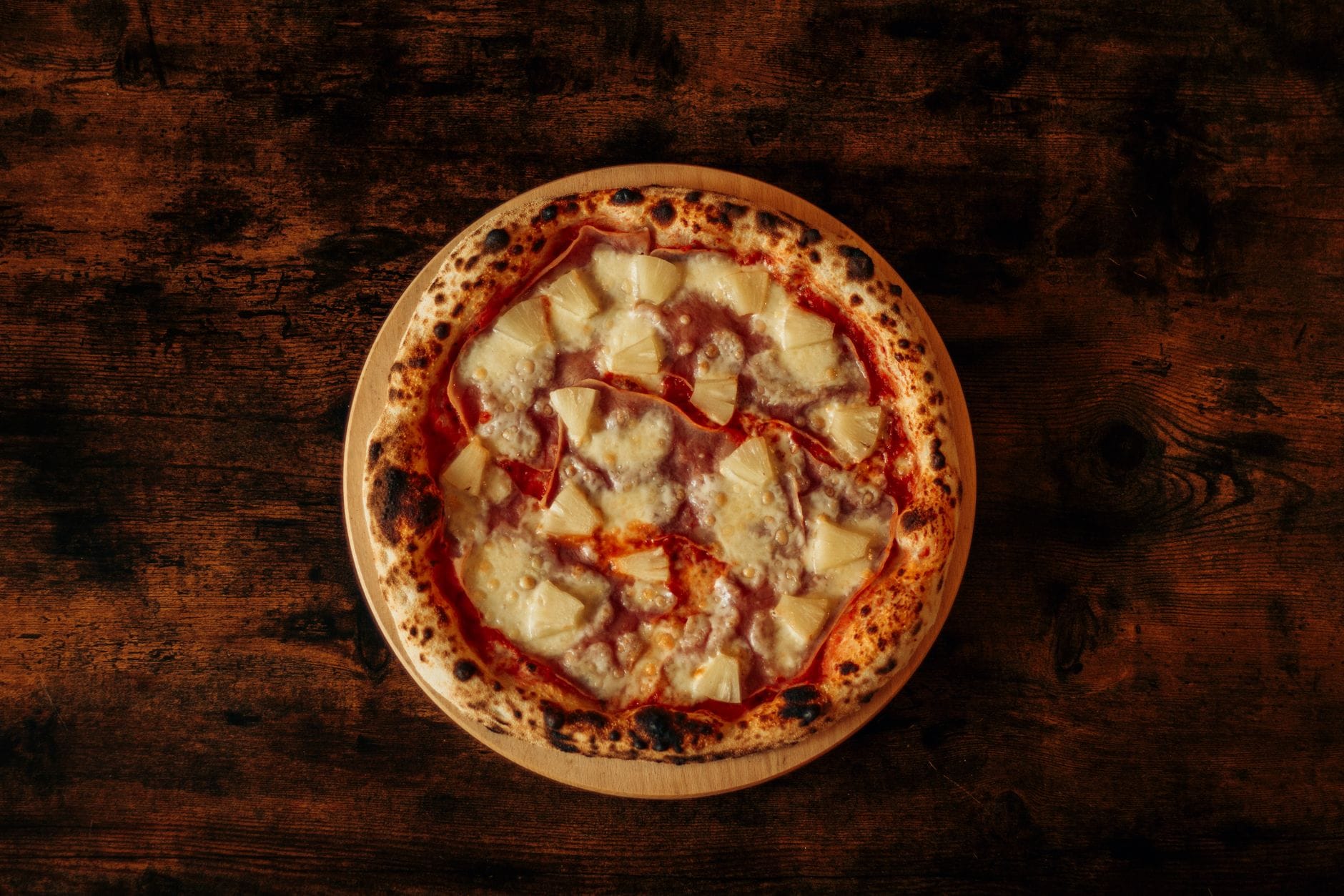 Pizza hawajska z ananasem i szynką na drewnianym stole z góry