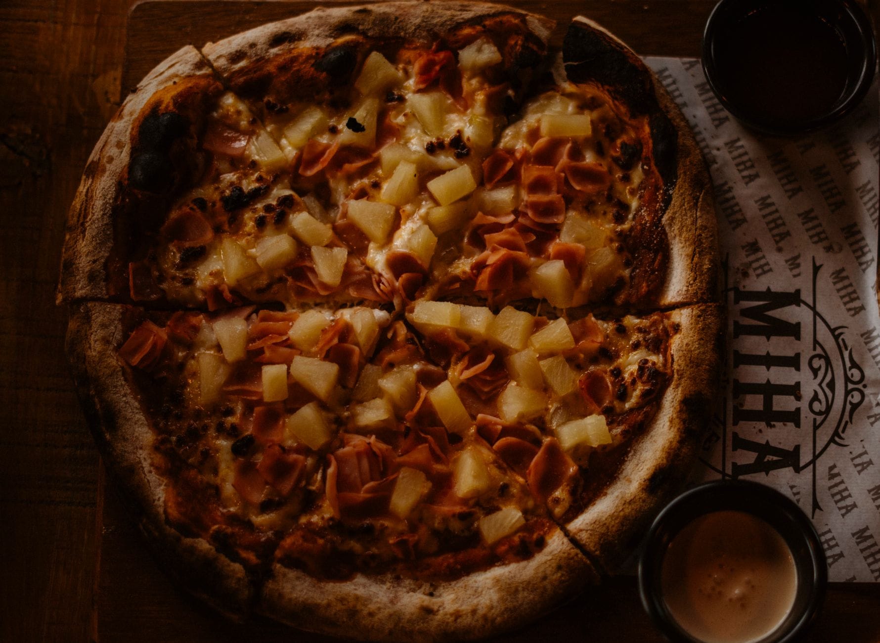 Pizza hawajska z szynką i ananasem na drewnianym stole