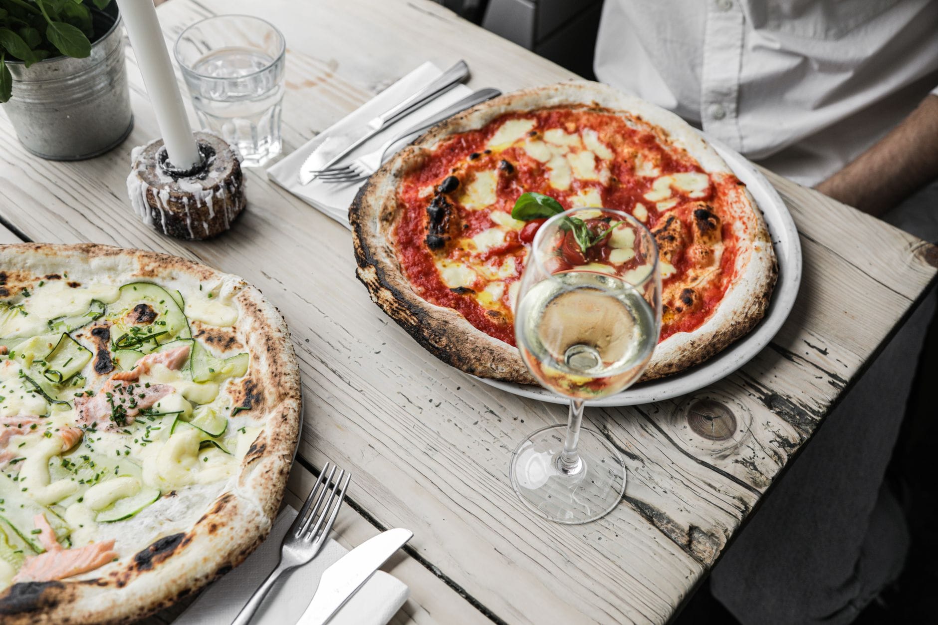 Pizza i kieliszki białego wina na rustykalnym drewnianym stole