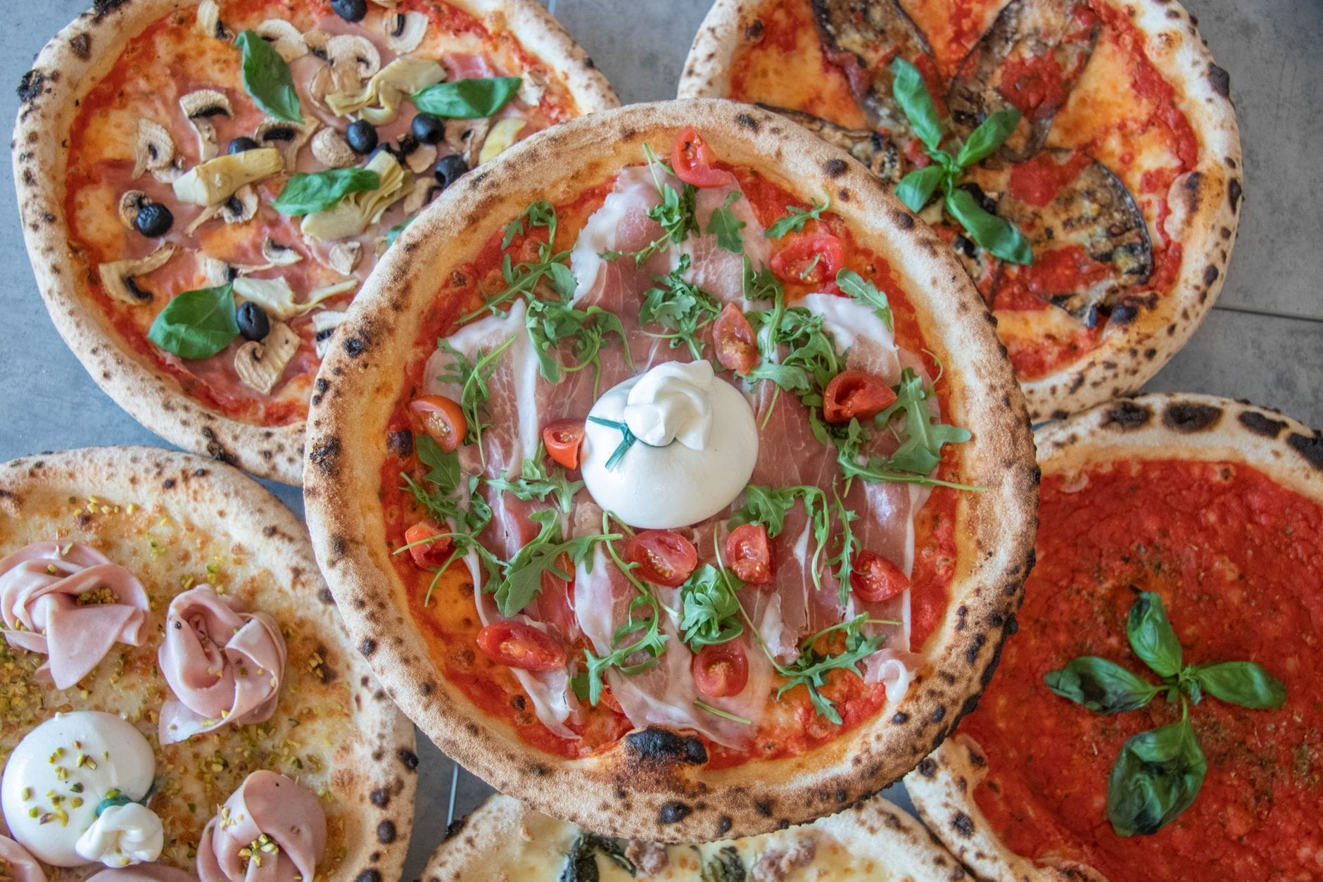Jak komponować pizze tematyczne, dobierając składniki pod konkretny region Włoch lub styl street foodu Różne pizze gourmet z włoskimi składnikami widziane z góry