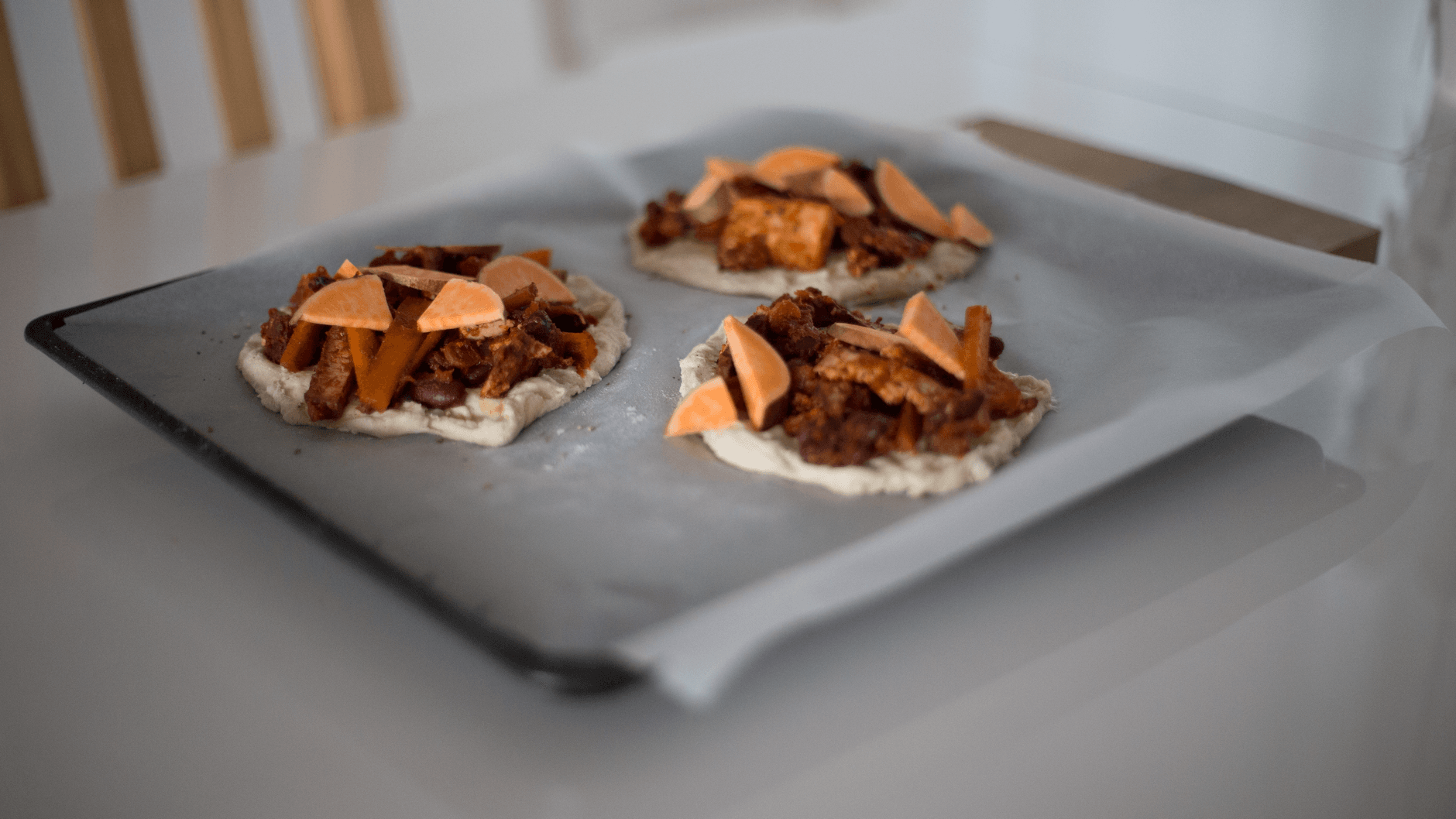 Blacha z surowymi mini pizzami z różnymi dodatkami przed włożeniem do piekarnika