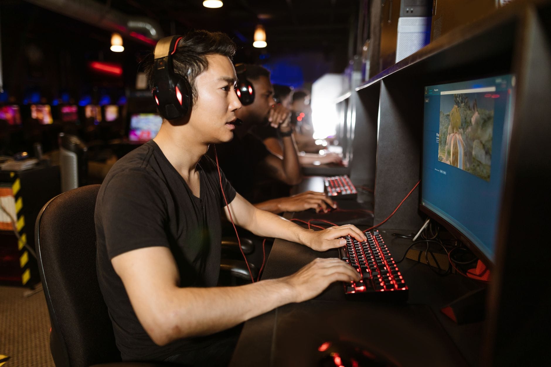 Jak zacząć przygodę z grami RPG na PC – poradnik dla początkujących graczy Grupa mężczyzn grających na komputerach w salonie gier internetowych