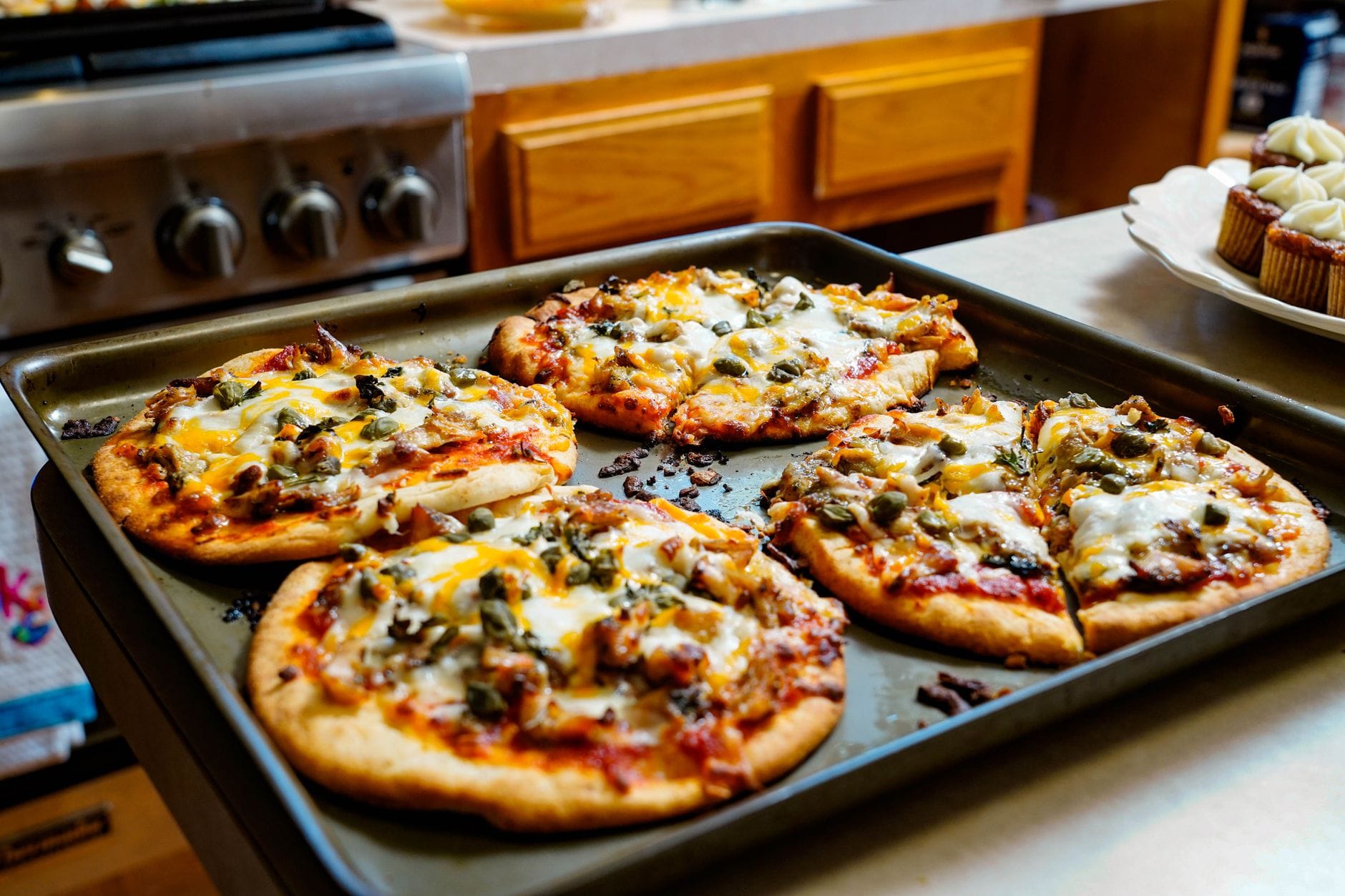 Jak piec kilka pizz pod rząd: zarządzanie temperaturą piekarnika i kolejnością wypieków Kilka świeżo upieczonych pizz z serem na kuchennym blacie