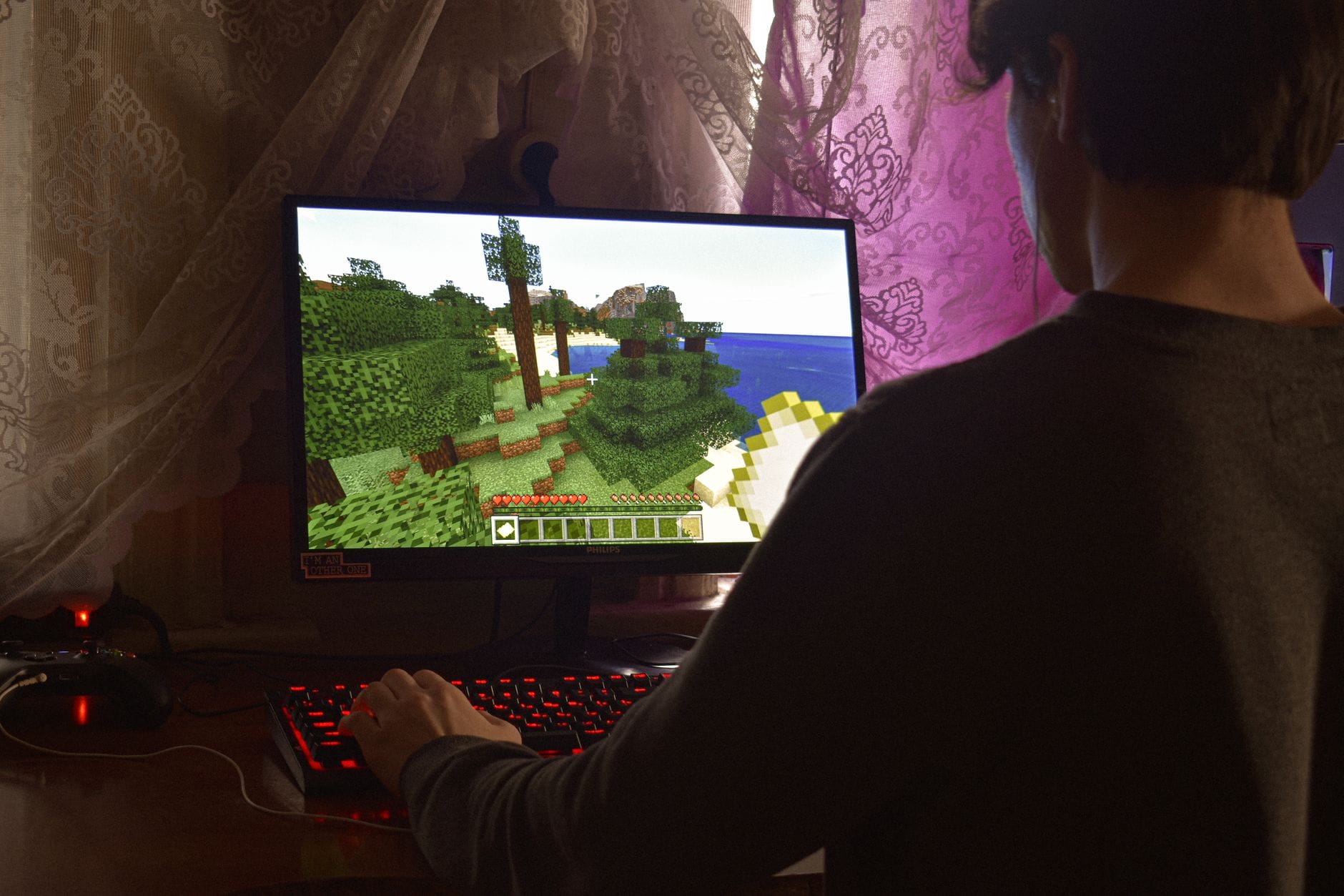 Młody mężczyzna skupiony na grze RPG przy komputerze w domu