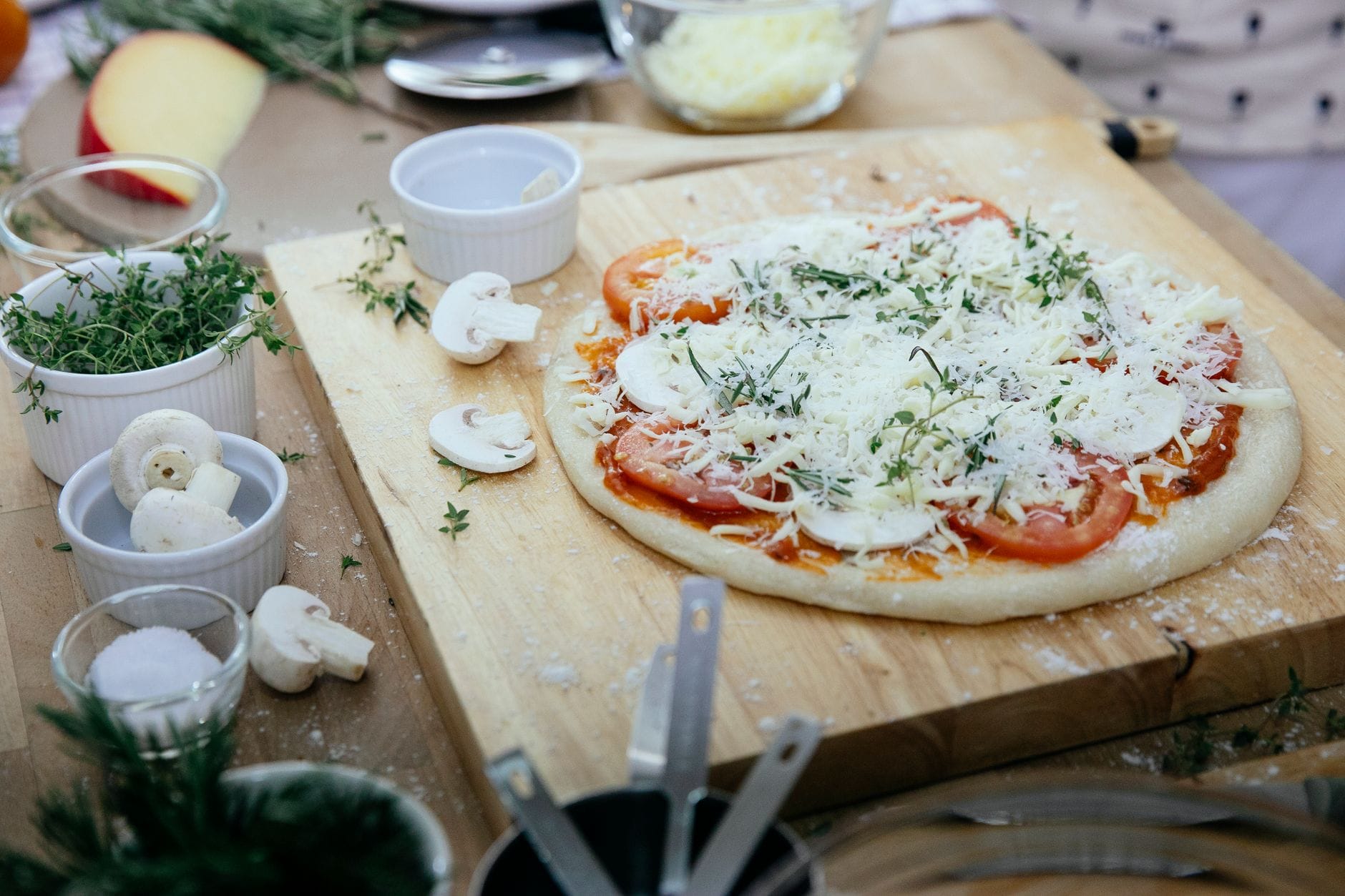 Surowa pizza z pieczarkami i pomidorami na drewnianej desce